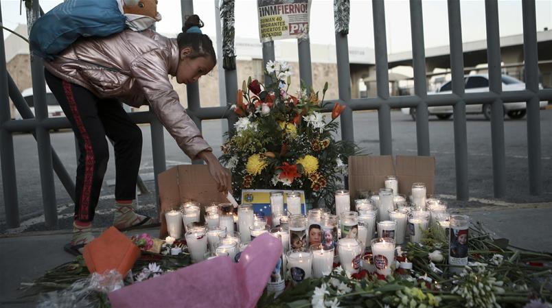 Una ragazza accende una candela in memoria dei migranti morti mentre puntavano verso gli USA