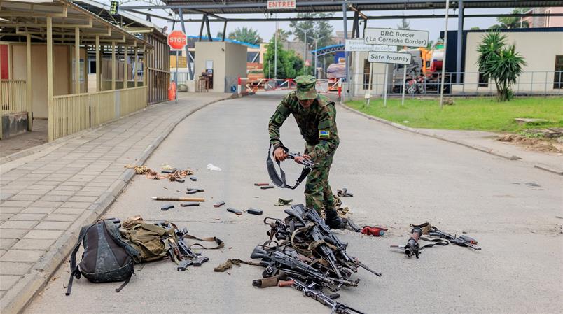 Un soldat rwandais inspecte les armes des forces congolaises s'étant rendus après la prise de Goma.